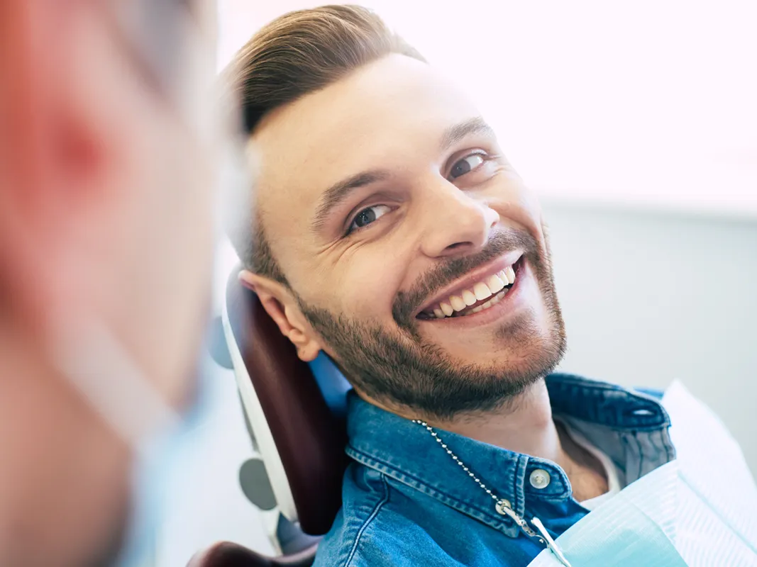 young adult man smiling and consulting with oral surgeon