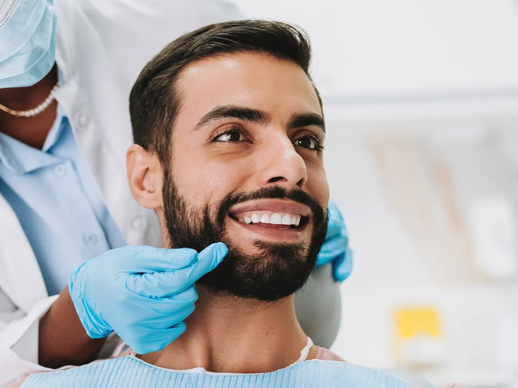 man with great smiling in patient chair discussing his teeth with the doctor