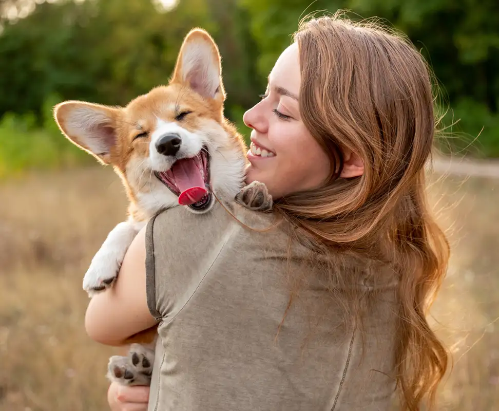 young woman holding a corgi and smiling