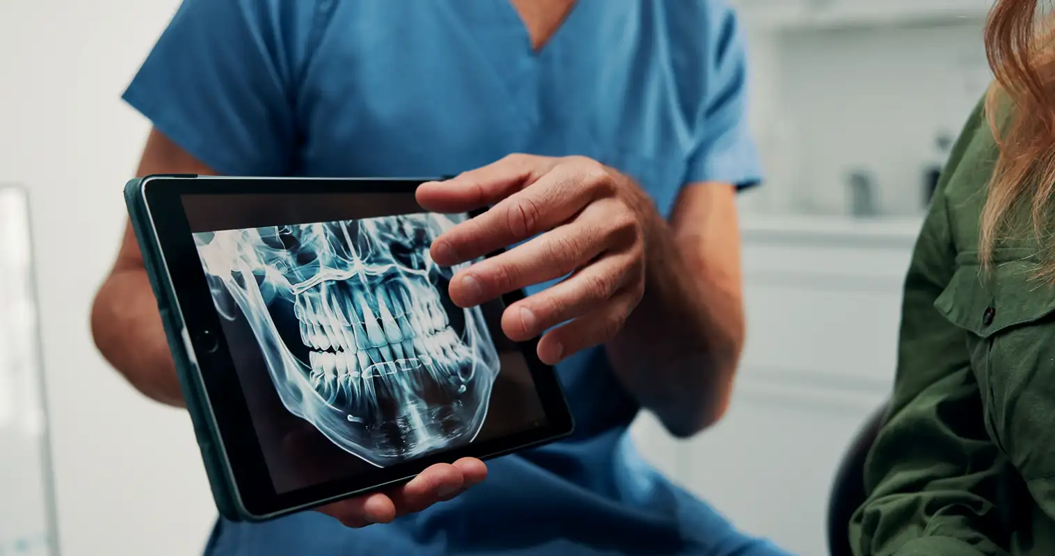oral surgeon showing patient an x-ray of their teeth on a tablet