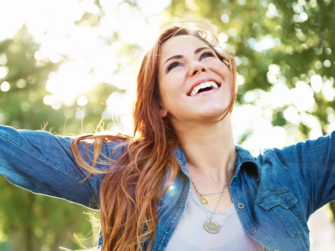 young woman stretching her arms outdoors and smiling